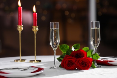 Photo of Romantic dinner table setting with glasses of champagne and red roses in restaurant