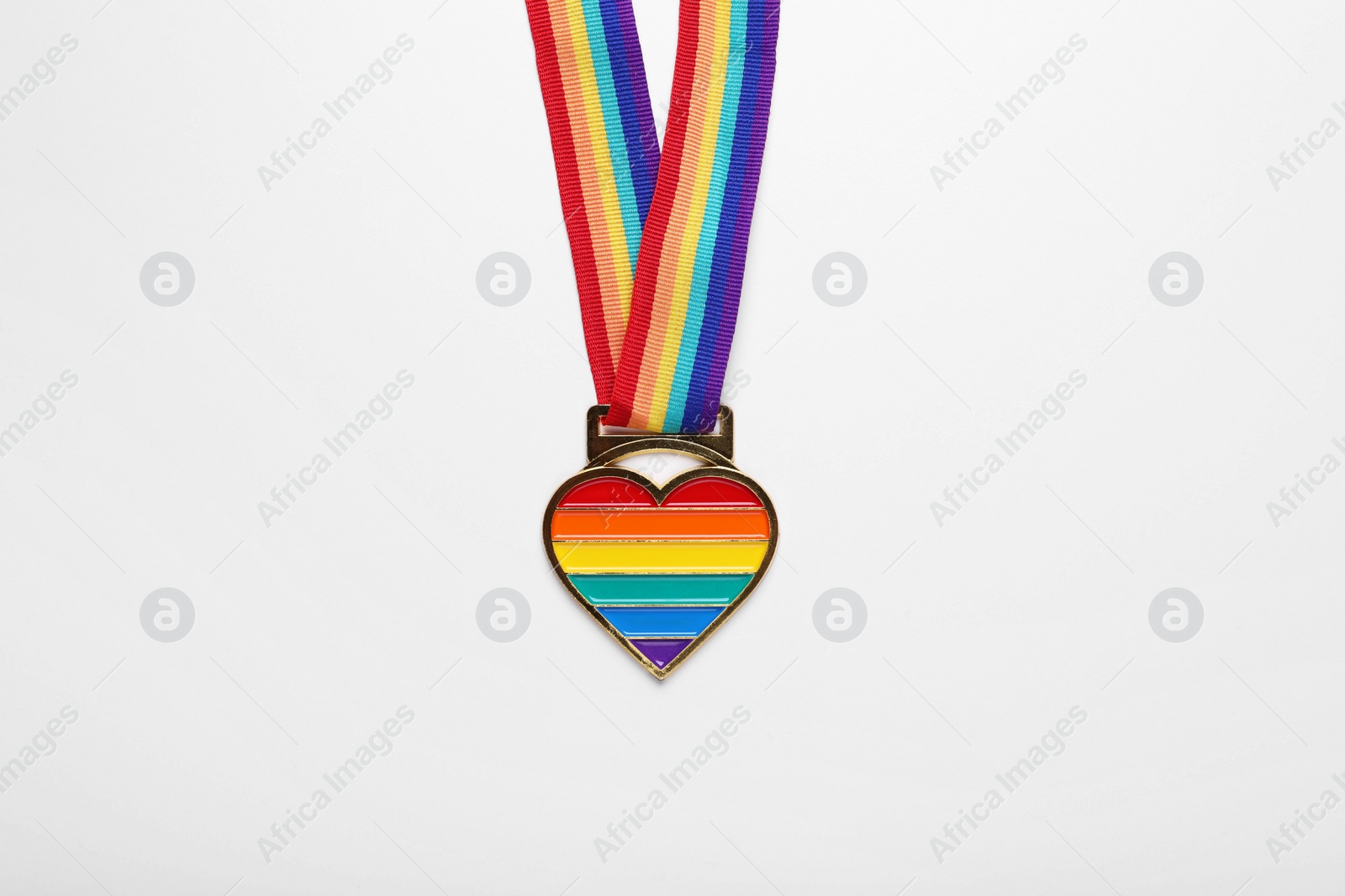 Photo of Rainbow ribbon with heart pendant on white background, top view. LGBT pride