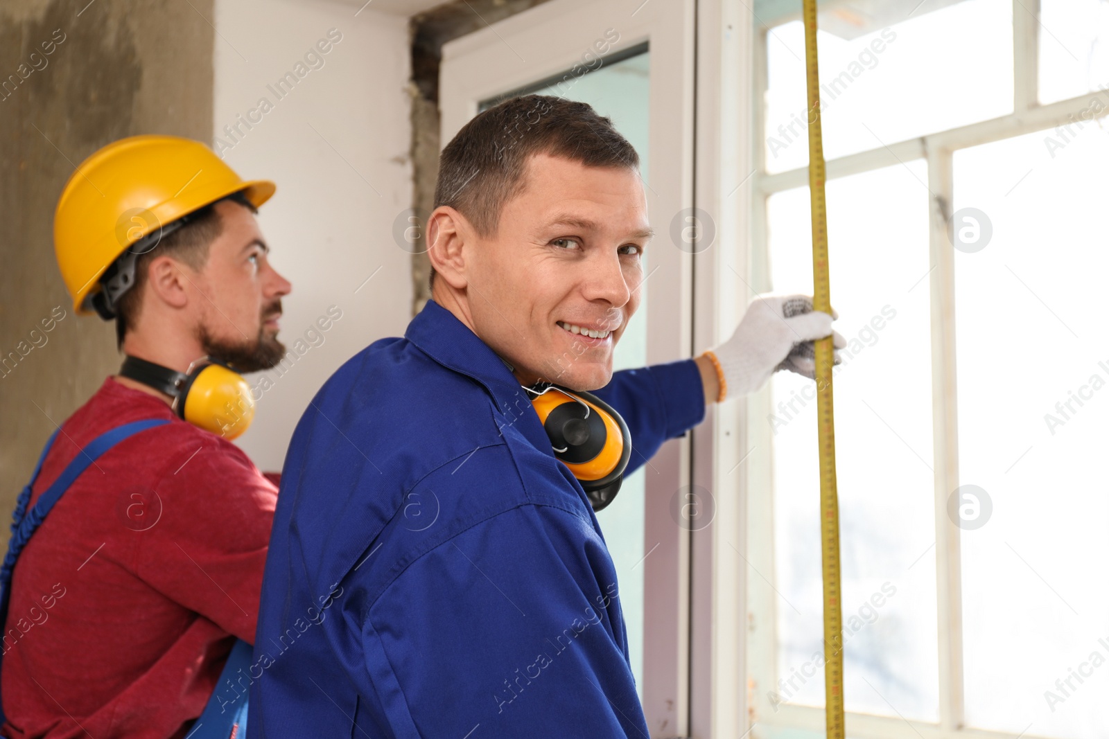 Photo of Workers taking measurement for window installation indoors