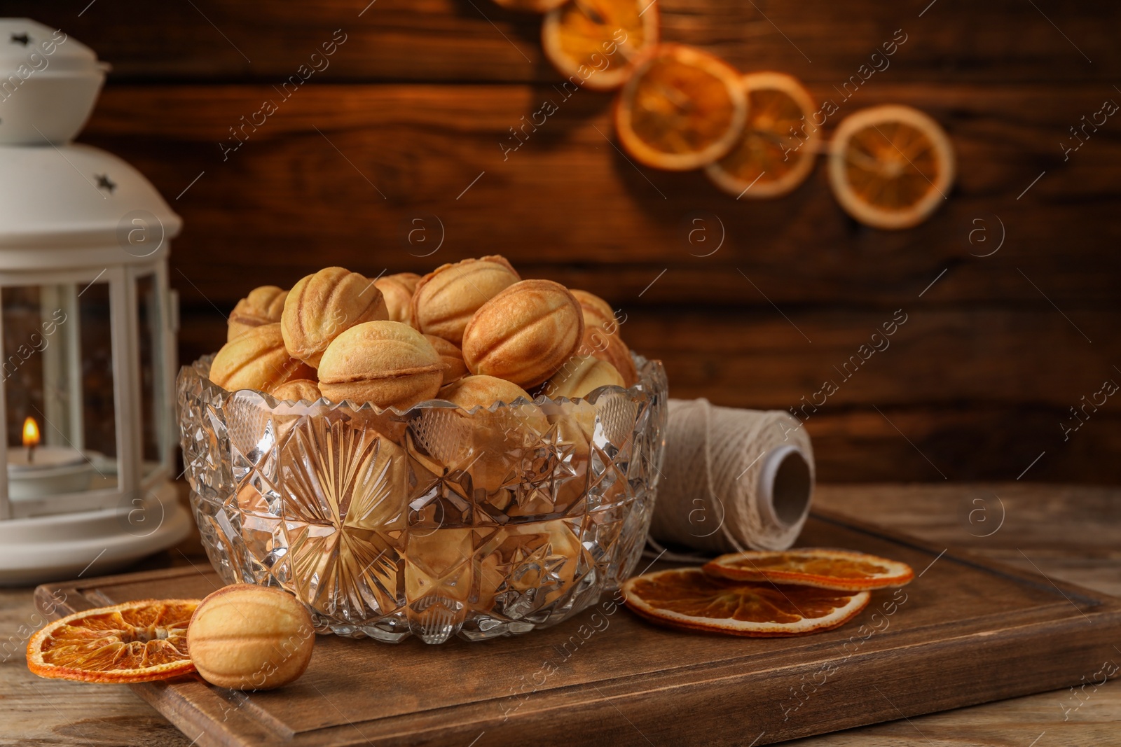 Photo of Bowl of delicious nut shaped cookies and dried orange slices on wooden table