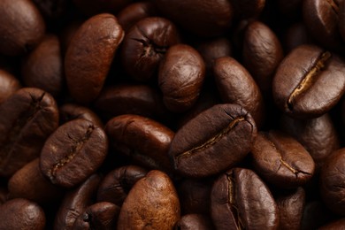 Photo of Aromatic roasted coffee beans as background, closeup