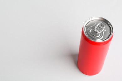 Photo of Energy drink in red can on light grey background, space for text