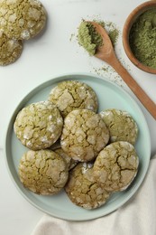 Photo of Plate with tasty matcha cookies and powder on white table, flat lay