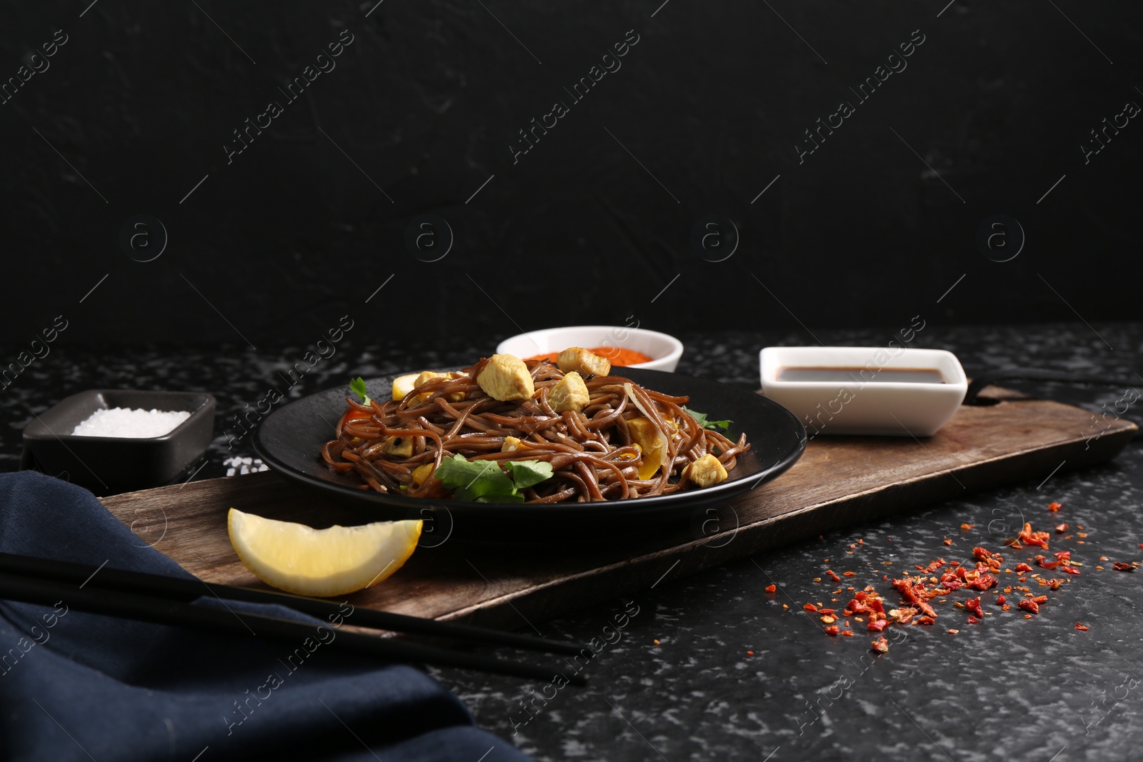 Photo of Stir-fry. Tasty noodles with vegetables and meat served on dark textured table