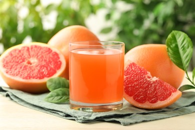 Glass of delicious grapefruit juice on white table against blurred background