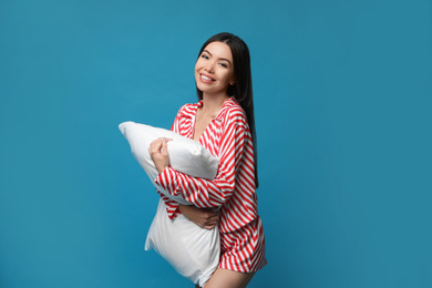 Beautiful Asian woman with pillow on blue background. Bedtime