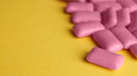 Photo of Sweet chewing gums on yellow background, closeup. Space for text