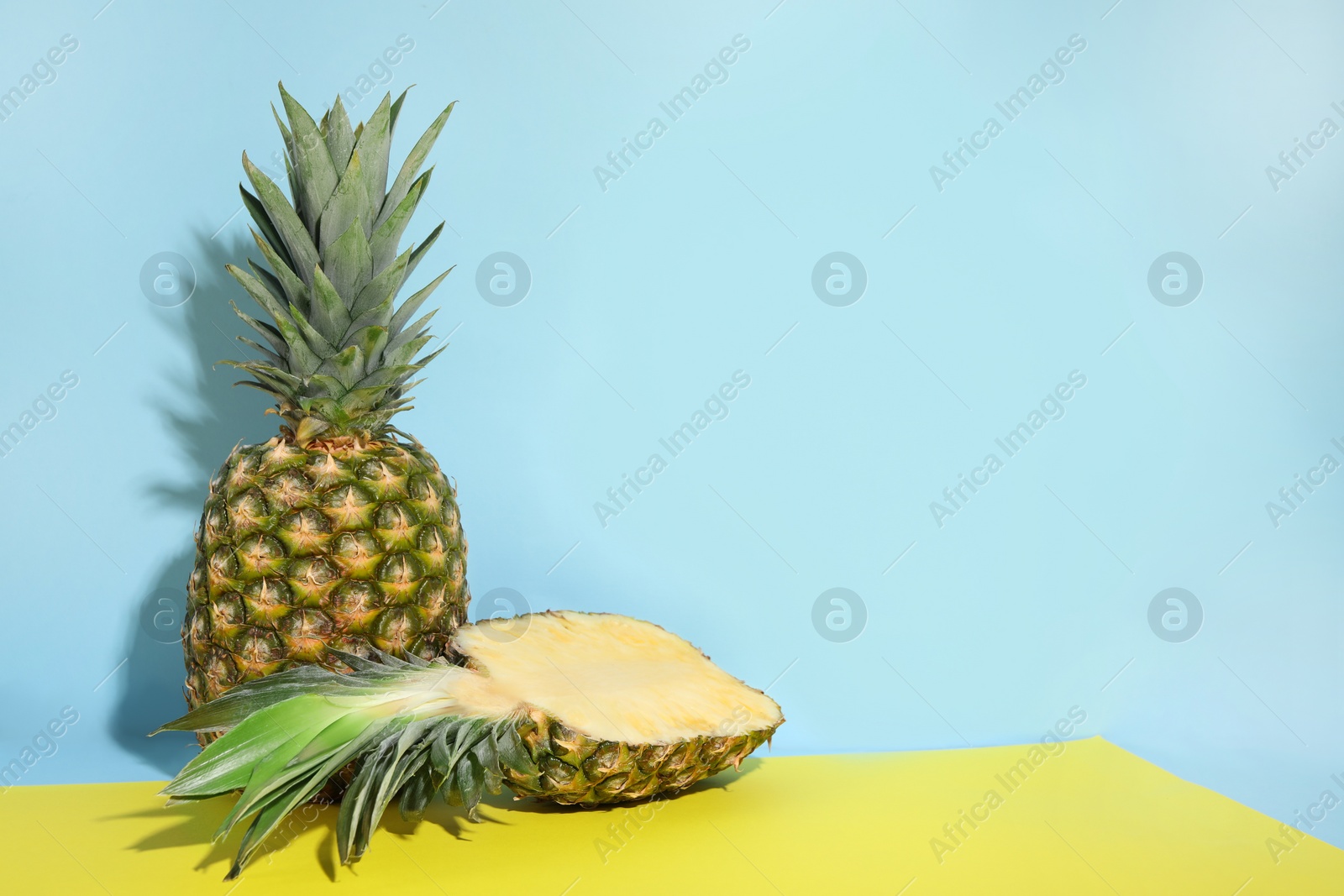 Photo of Whole and cut ripe pineapples on color background, space for text