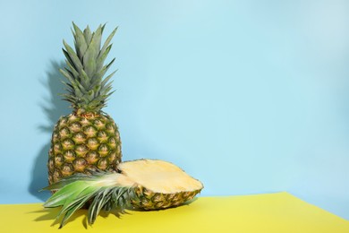 Whole and cut ripe pineapples on color background, space for text