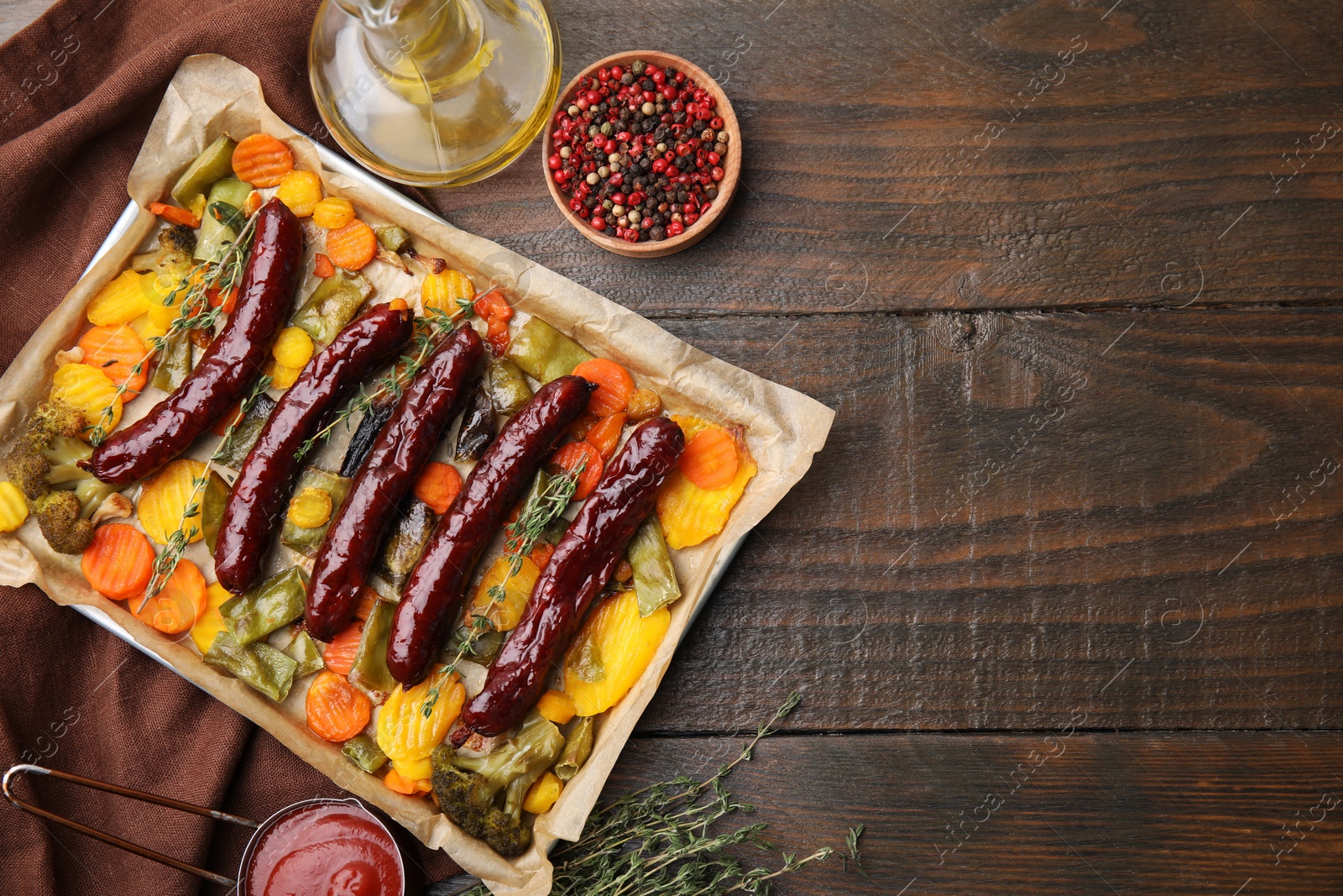 Photo of Baking tray with delicious smoked sausages and ingredients on wooden table, flat lay. Space for text