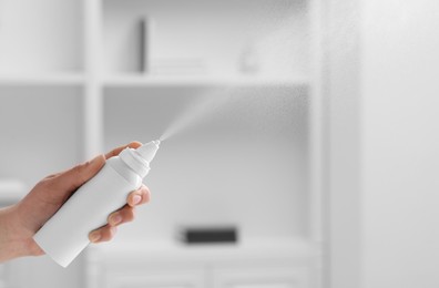 Woman using nasal spray indoors, closeup. Space for text