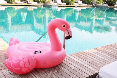 Photo of Float in shape of flamingo on wooden deck near swimming pool at luxury resort