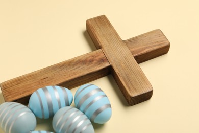 Wooden cross and painted Easter eggs on beige background