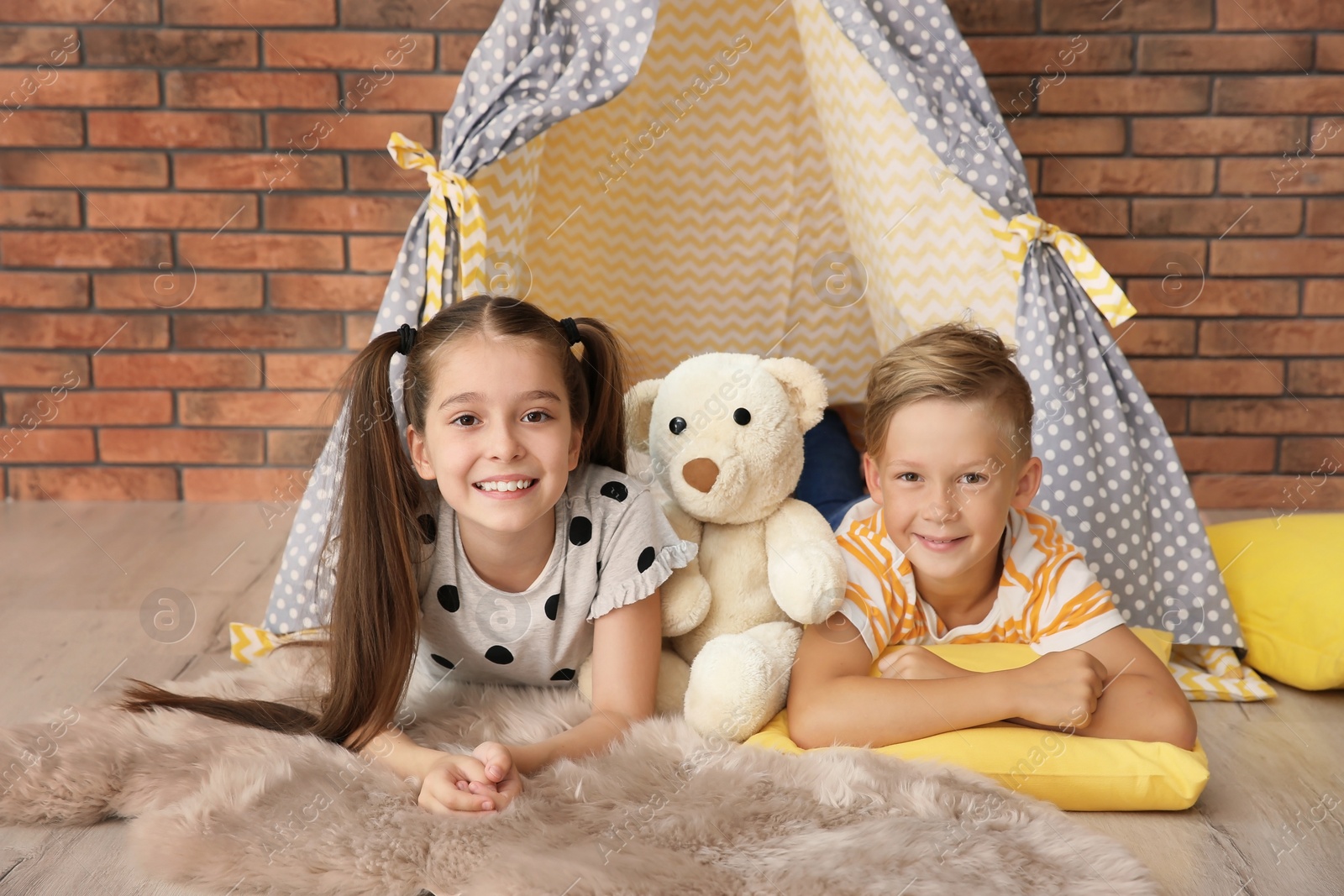 Photo of Playful little children in handmade tent indoors