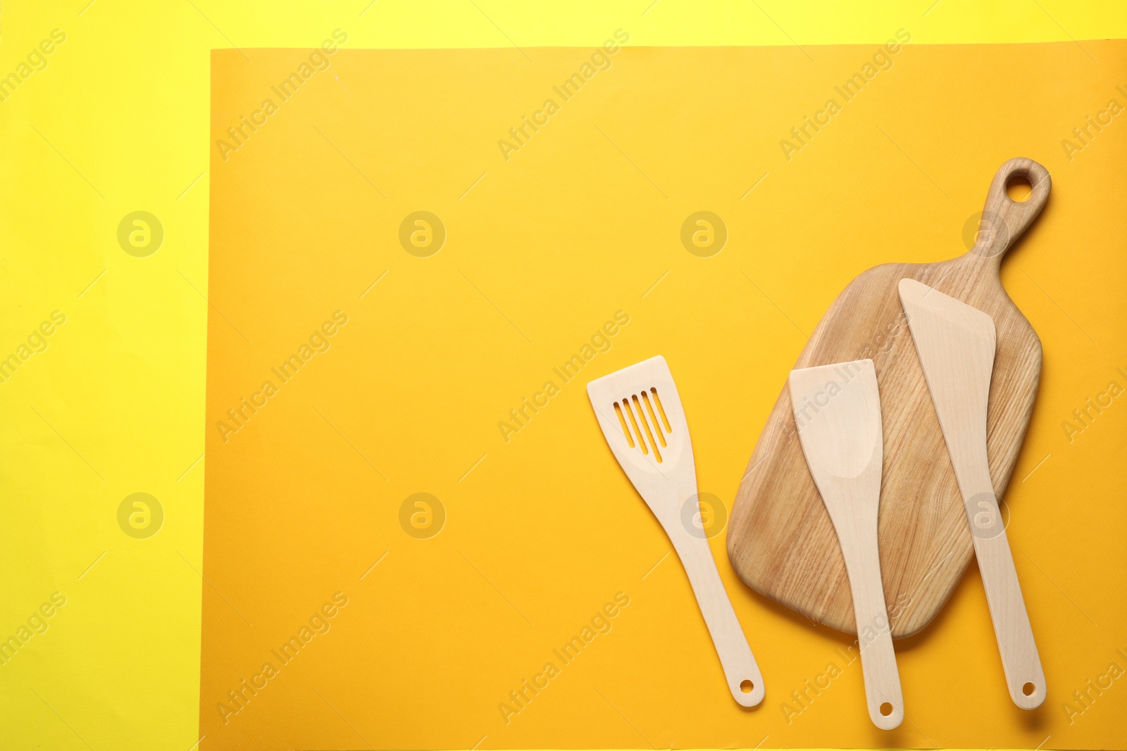 Photo of Different wooden spatulas and board on color background, flat lay. Space for text