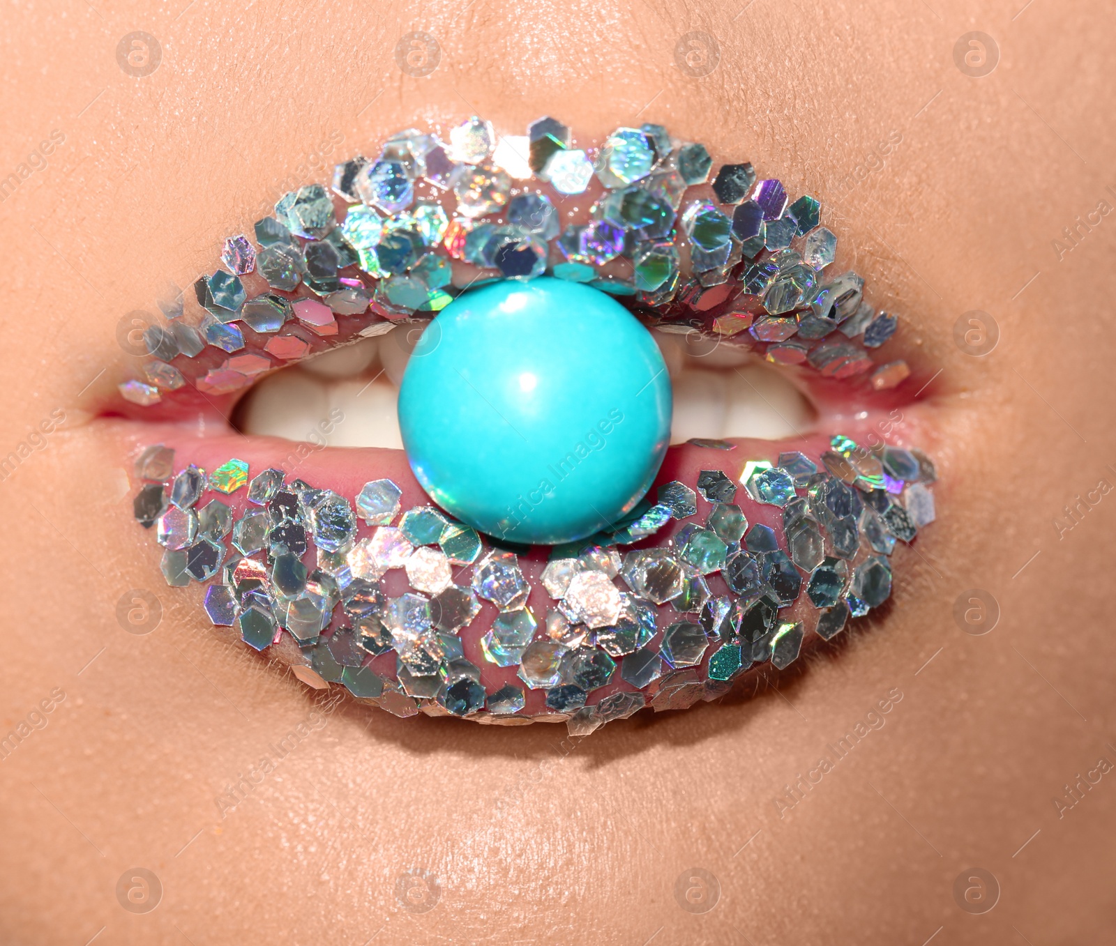 Photo of Beautiful young model with extravagant makeup holding candy in lips, closeup