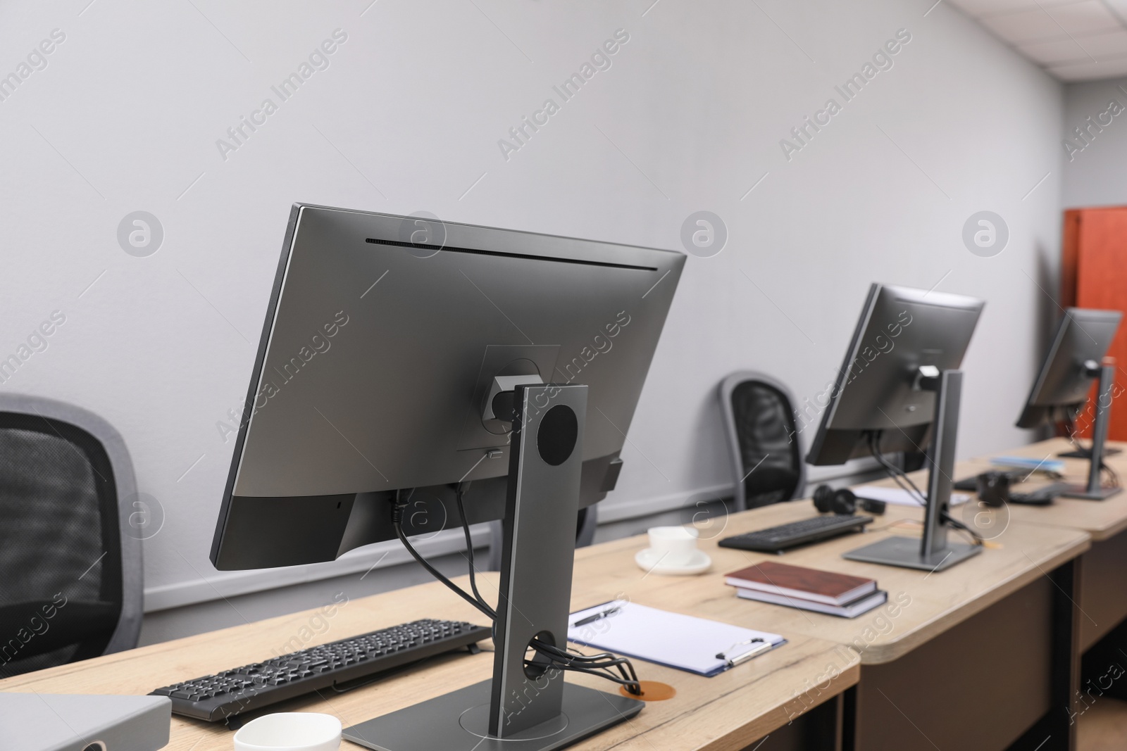 Photo of Open office interior. Modern workplaces with computers near light grey wall