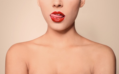 Photo of Beautiful young woman with red glossy lips on color background, closeup