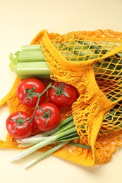 String bag with different vegetables on beige background, closeup