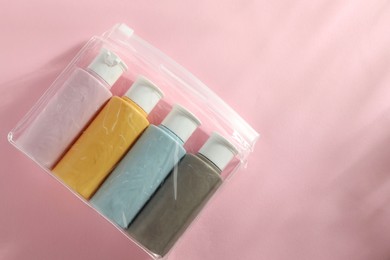 Photo of Cosmetic travel kit in plastic bag on pink background, top view. Space for text