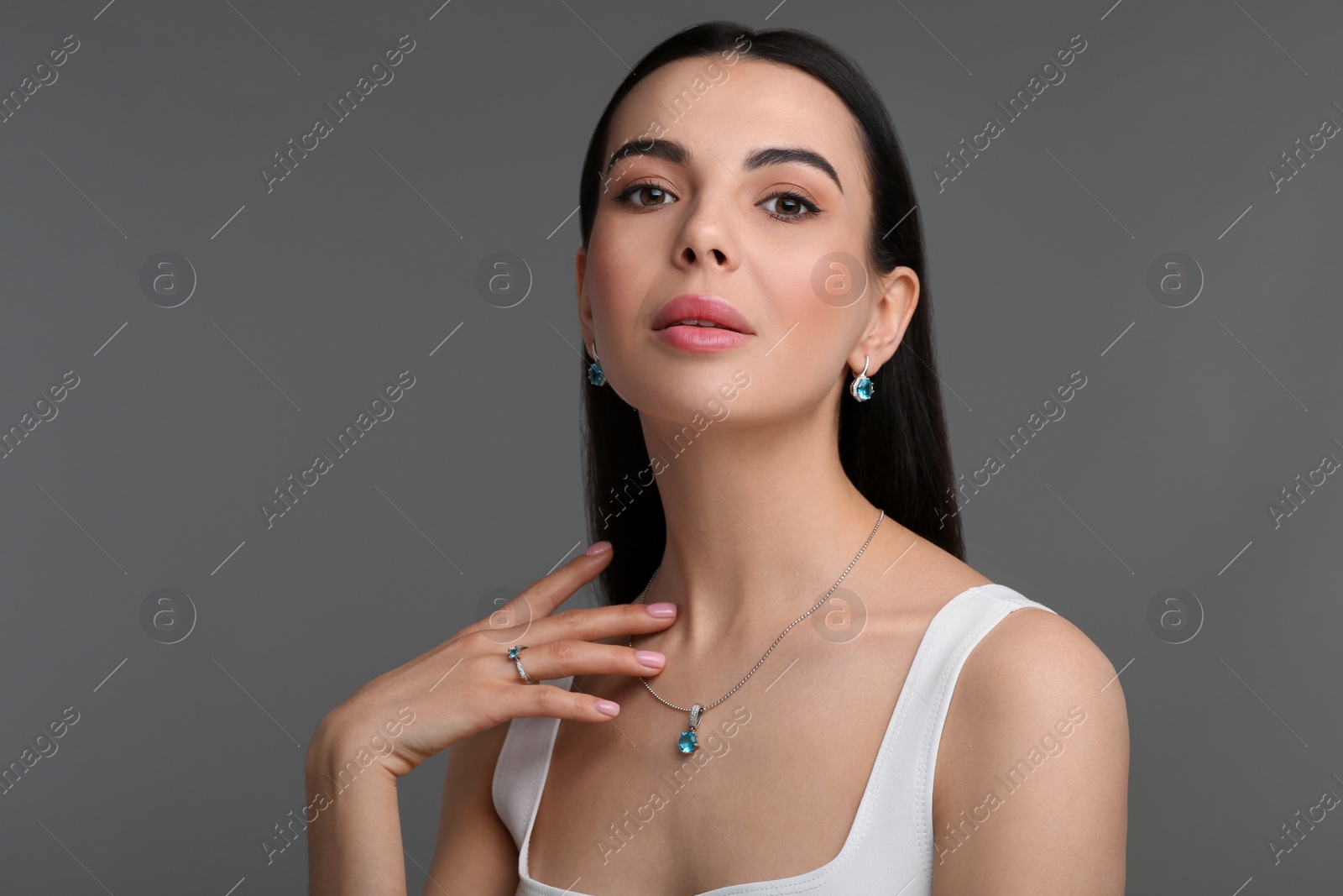 Photo of Beautiful young woman with elegant jewelry on dark grey background