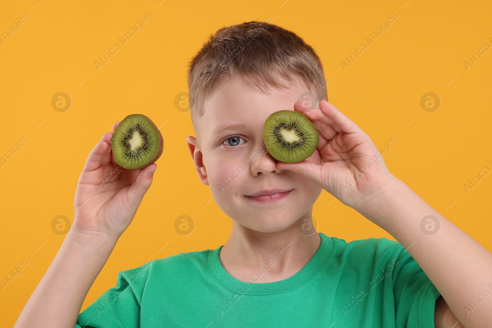 Photo of Boy with fresh kiwi on orange background