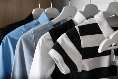 Photo of Stylish boy's clothes hanging in wardrobe, closeup