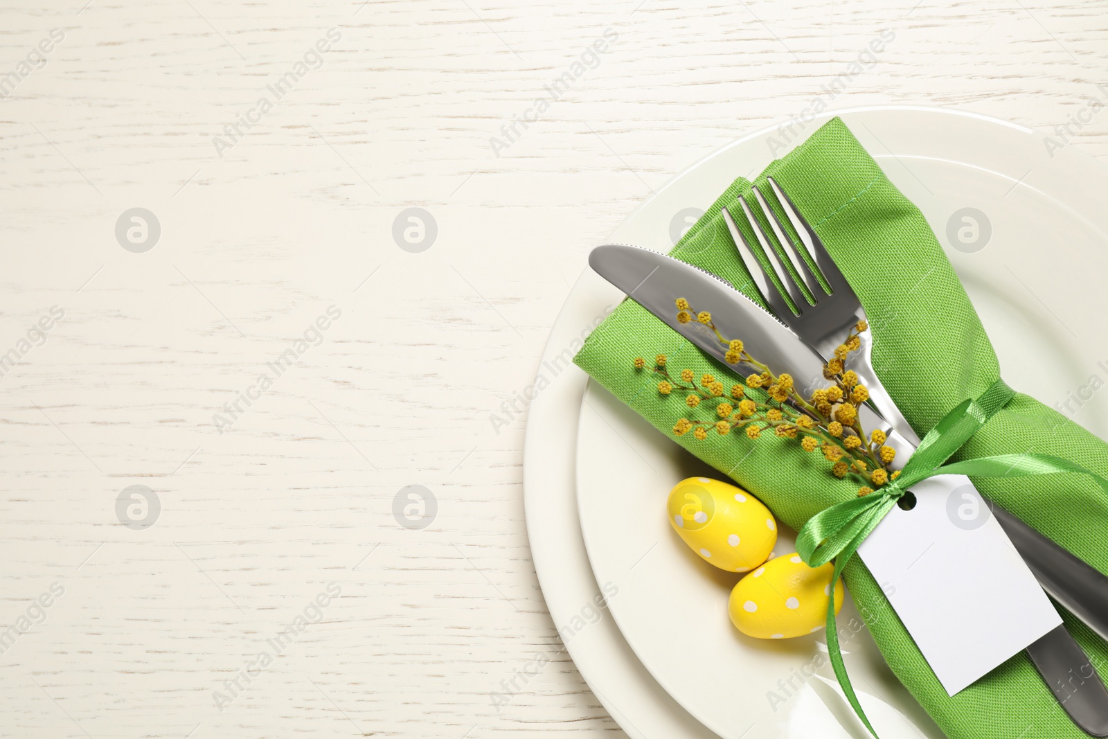 Photo of Festive Easter table setting with beautiful mimosa flowers and painted eggs, top view. Space for text