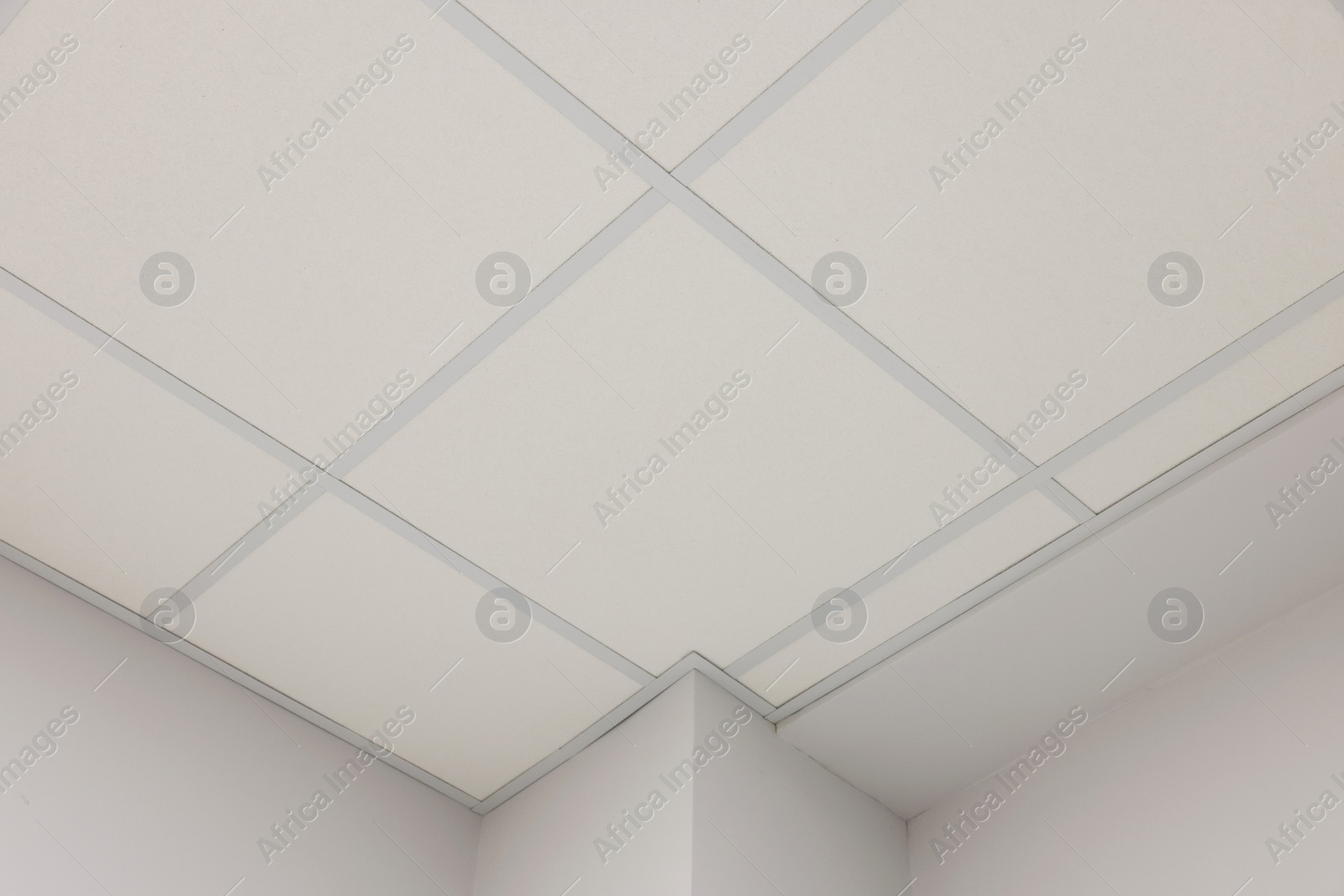 Photo of White ceiling with PVC tiles indoors, low angle view