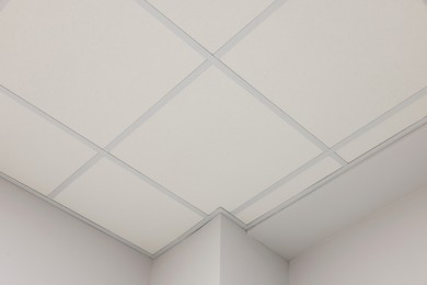 Photo of White ceiling with PVC tiles indoors, low angle view