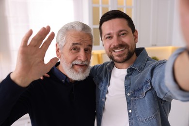 Photo of Happy son and his dad taking selfie at home