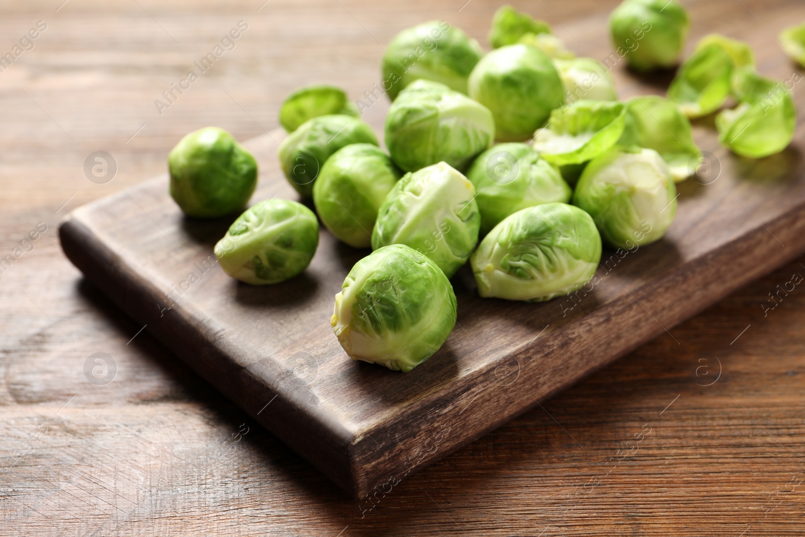 Photo of Board with Brussels sprouts on wooden table, closeup