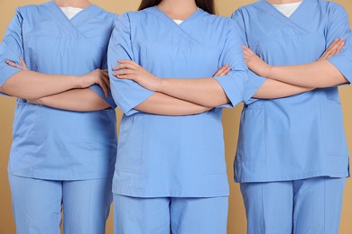 Nurses in medical uniforms on light brown background, closeup