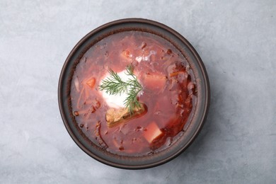 Photo of Tasty borscht with sour cream in bowl on light grey table, top view