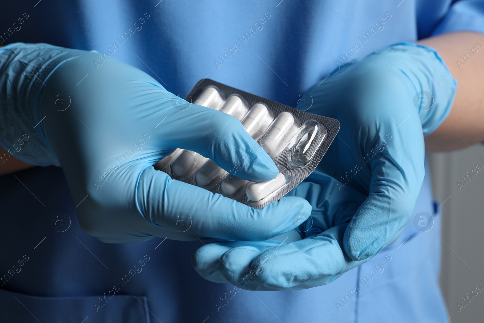 Photo of Doctor taking pill out from blister pack on grey background, closeup