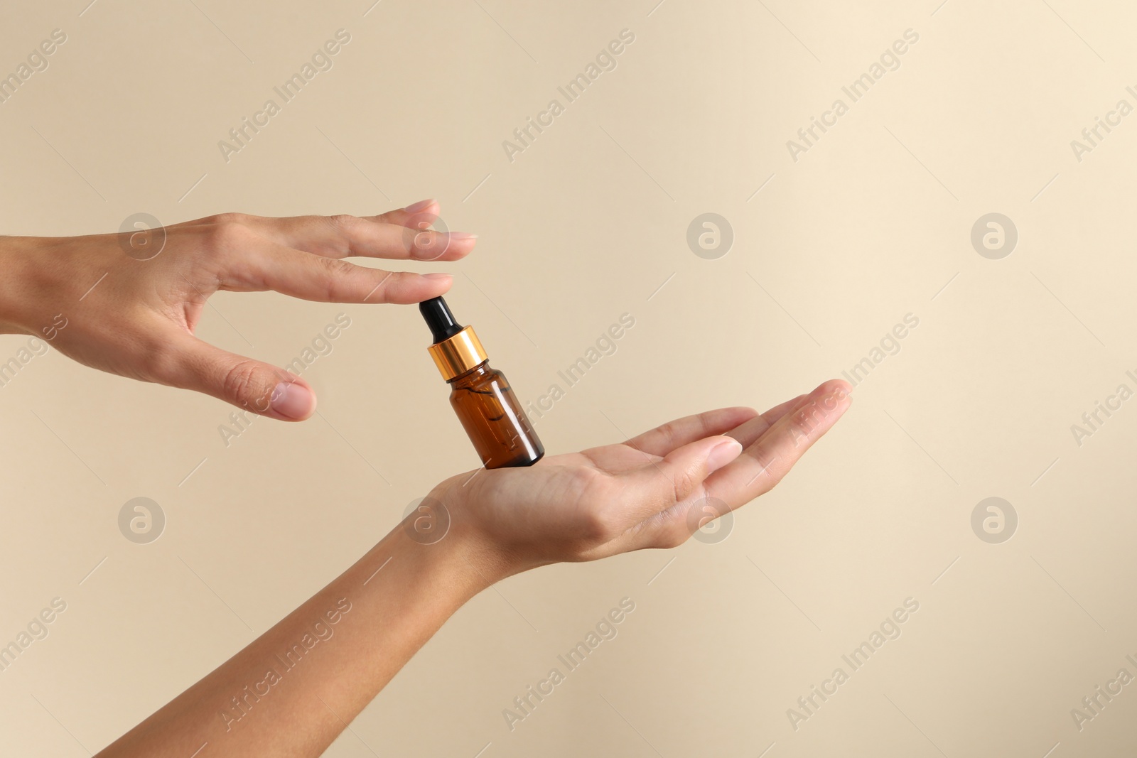 Photo of Woman with bottle of cosmetic serum on beige background, closeup. Space for text