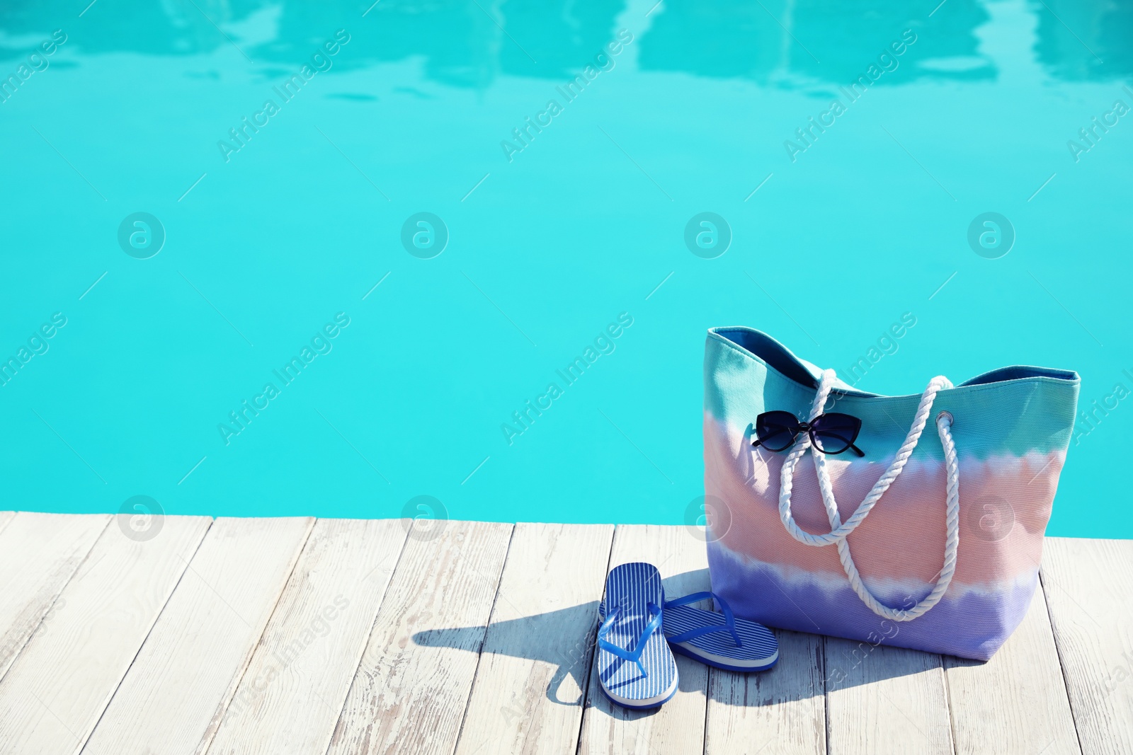 Photo of Beach accessories near swimming pool on sunny day. Space for text