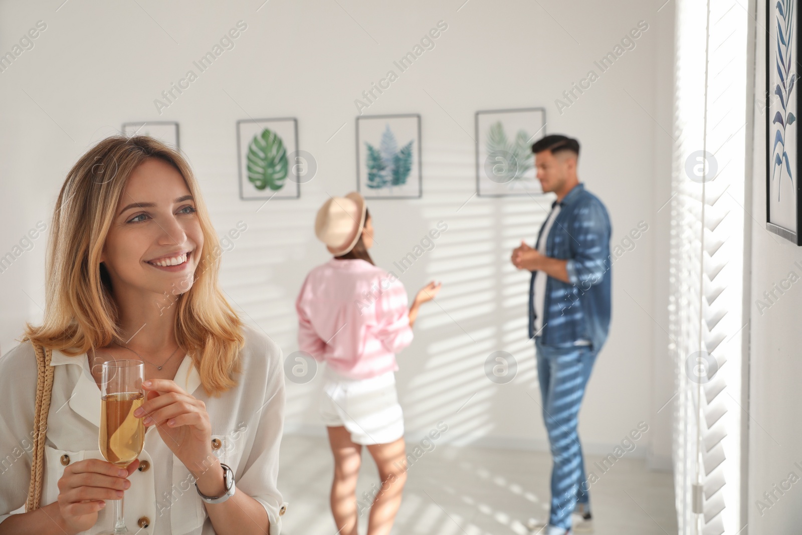 Photo of Young woman with glass of champagne at exhibition in art gallery