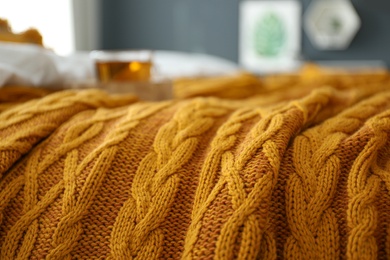 Knitted orange plaid on bed indoors, closeup