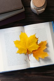 Book with beautiful leaves as bookmark on wooden table, flat lay