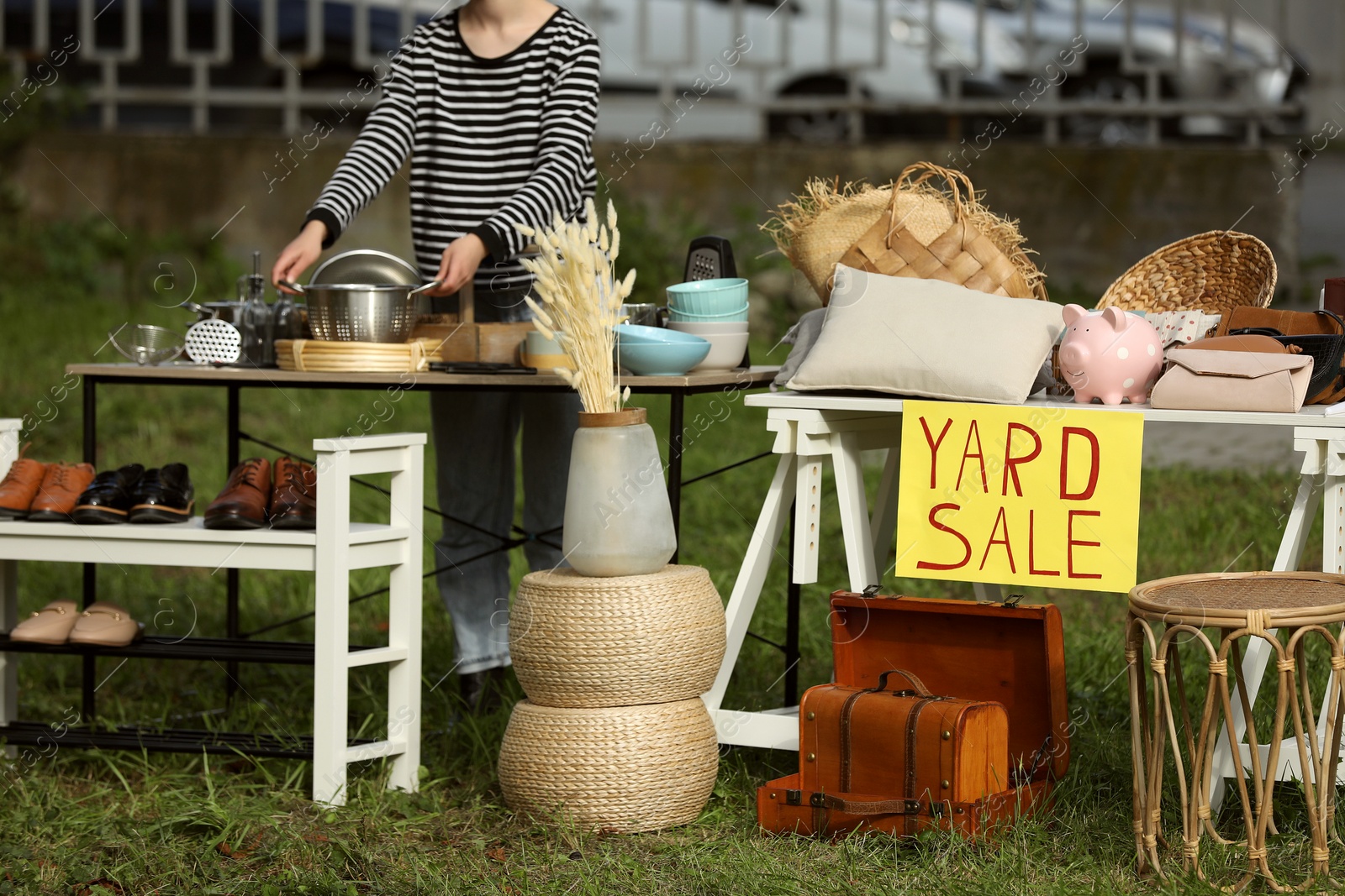 Photo of Woman near tables with different stuff on garage sale outdoors