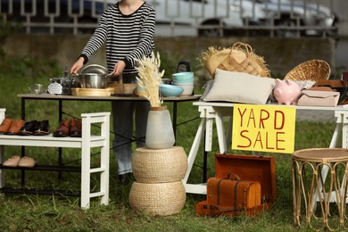 Photo of Woman near tables with different stuff on garage sale outdoors