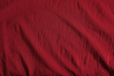 Crumpled dark red fabric as background, top view