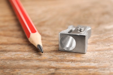 Photo of Metal sharpener and pencil on wooden table, closeup