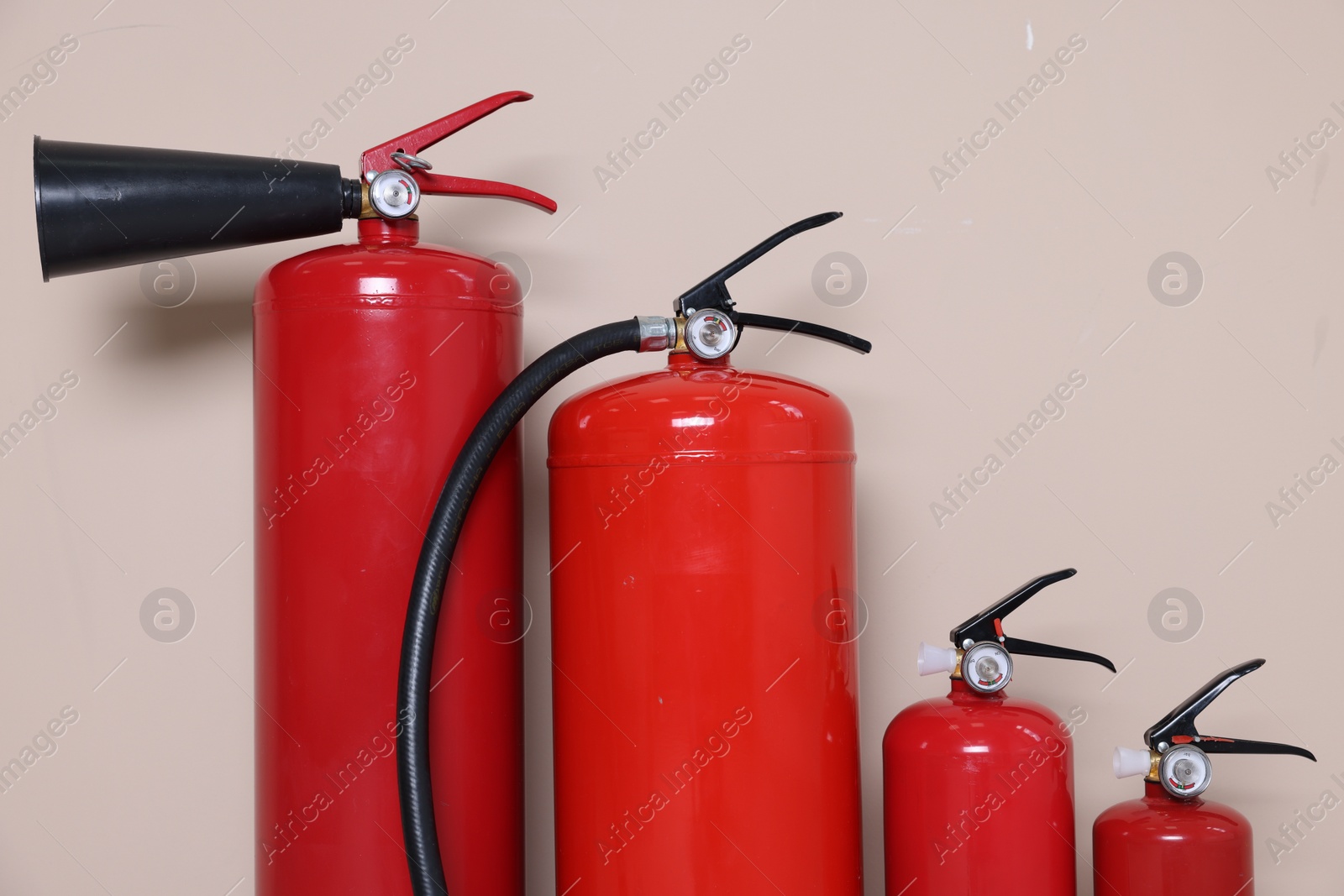 Photo of Set of fire extinguishers on beige background