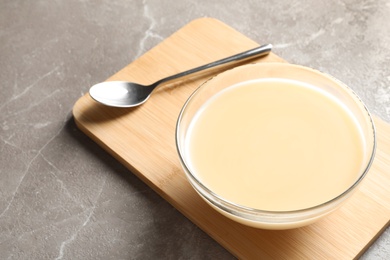 Photo of Bowl of condensed milk served on table, space for text. Dairy products