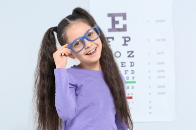 Photo of Little girl with glasses visiting children's doctor in clinic, space for text. Eye examination