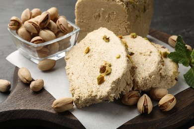 Photo of Tasty halva with pistachios and mint on grey table, closeup