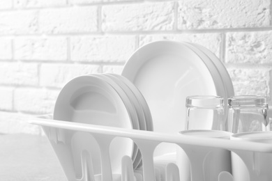 Photo of Dish drainer with clean plates on table, closeup