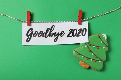 Photo of Flat lay composition with phrase Goodbye 2020 and gingerbread cookie on green background